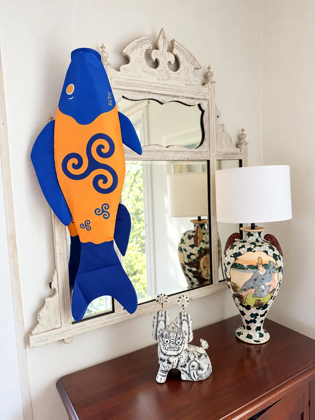 Triskel hanging in front of an antique mirror, above a chest of drawers