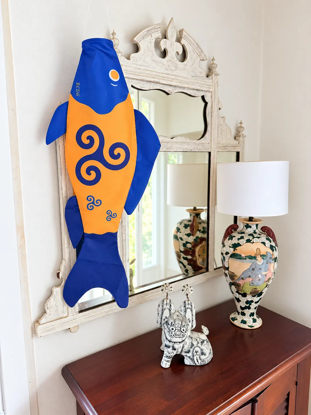 Triskel in front of a mirror, next to a lamp and a vase