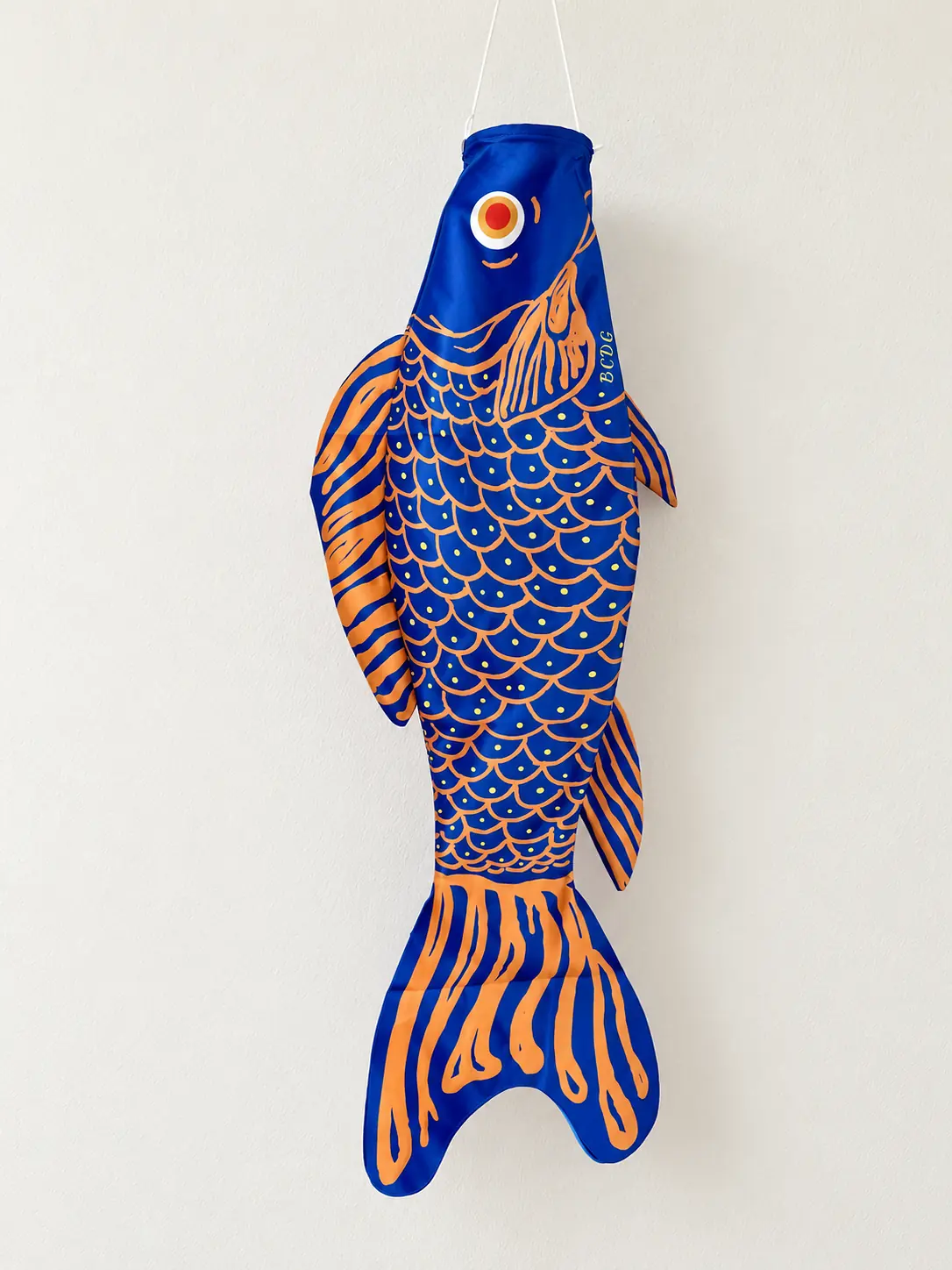 Écailles Bleues et Oranges hanging on an ivory wall